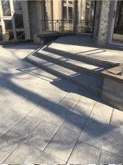 A patio with concrete stairs and a bench in front of a house