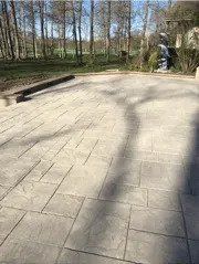 A patio with a bench and trees in the background