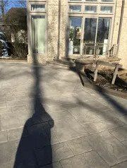 A patio with a table and chairs, and a shadow of a tree on it