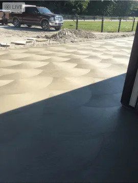 A truck is driving down a dirt road next to a field