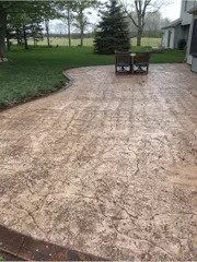 A beautiful concrete patio with a table and chairs in the backyard of a house