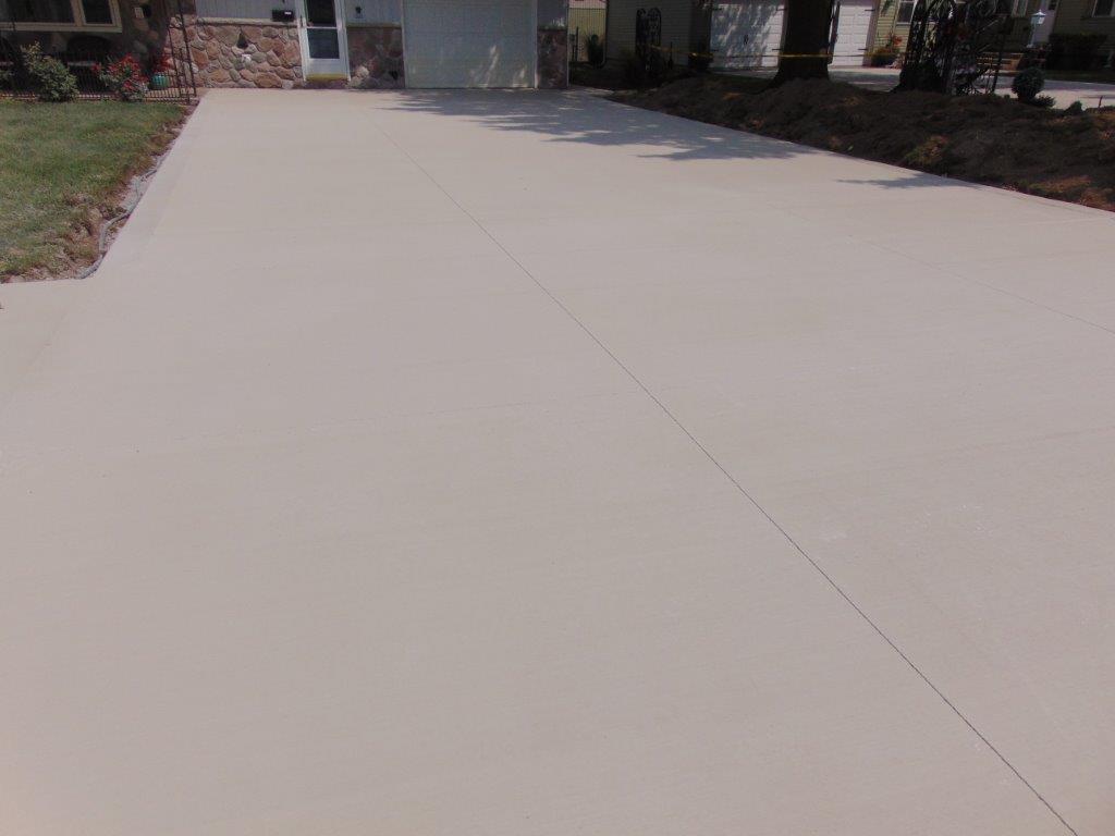 A concrete driveway leading to a house on a sunny day