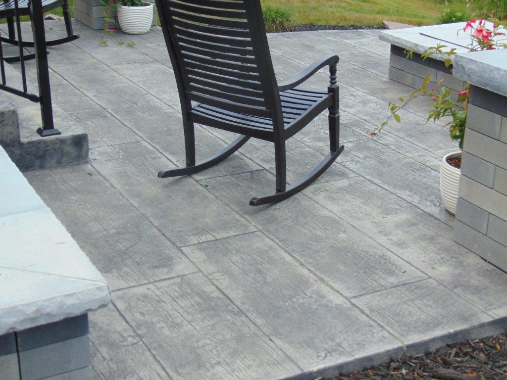 A rocking chair is sitting on a patio next to a bench