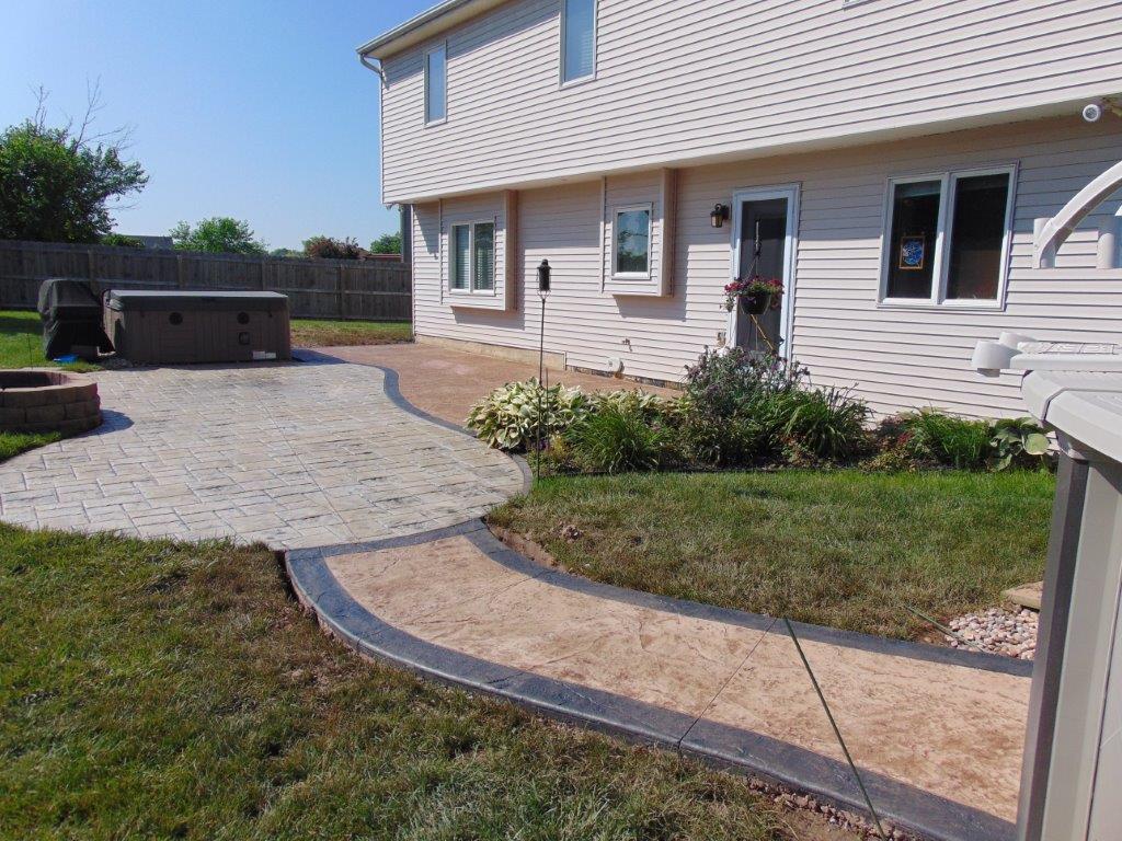 A house with a walkway leading to it and a hot tub in the backyard