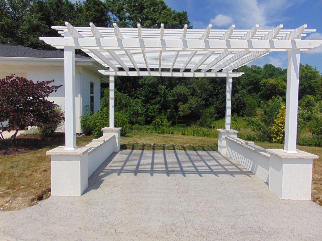 A white pergola with a bench underneath it