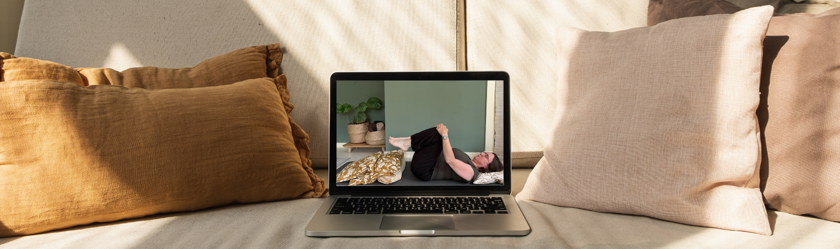 Een vrouw bekijkt op een laptop een yogavideo van De Online Yogaschool
