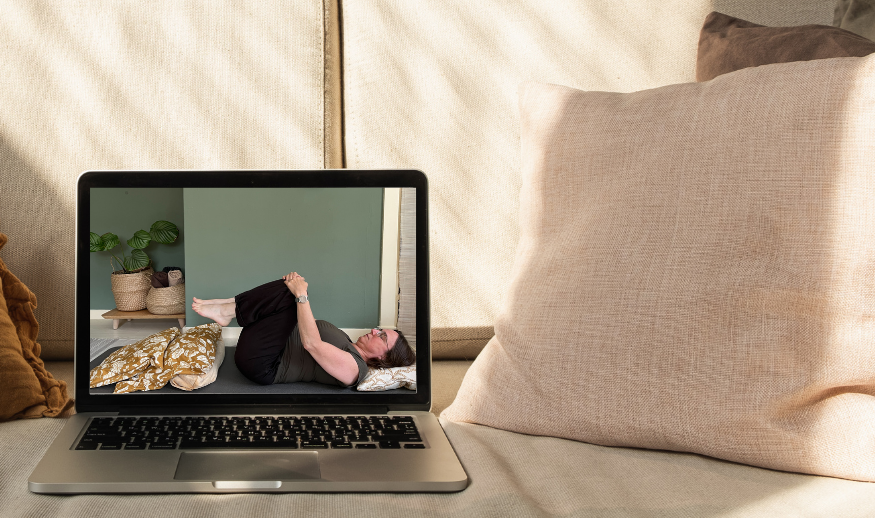 Een vrouw bekijkt op een laptop een yogavideo van De Online Yogaschool