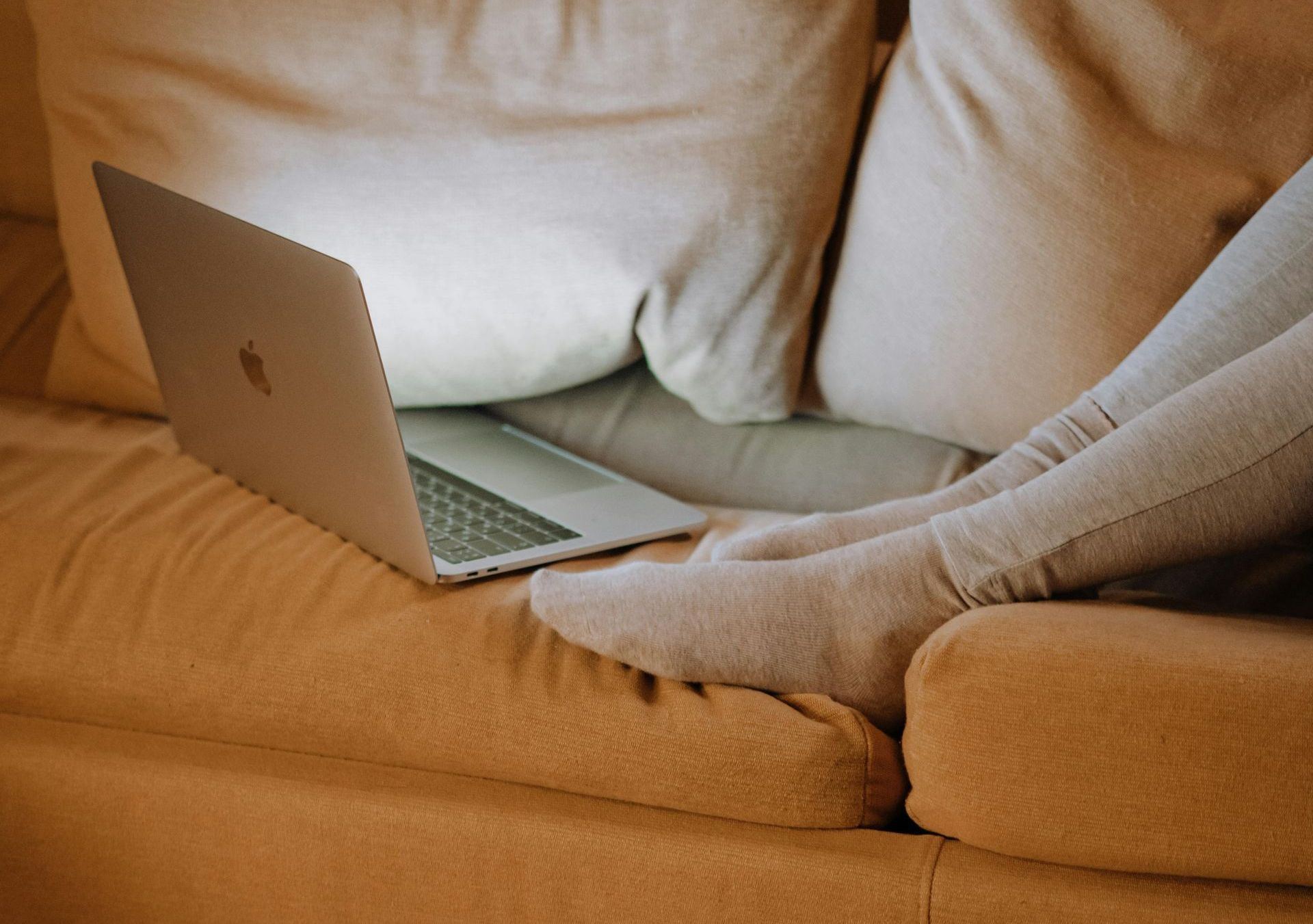 Een persoon zit op een bank en gebruikt een laptop.