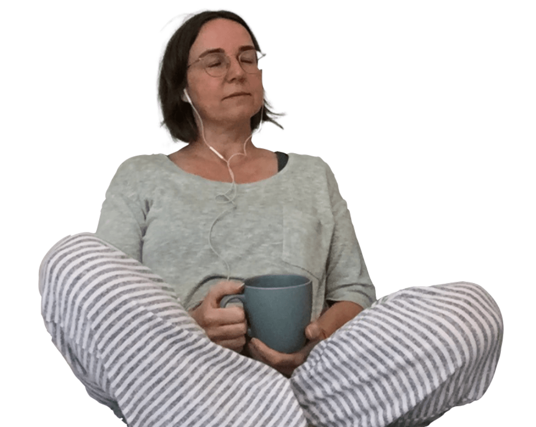 Vrouw met bril zit, houdt een mok vast, draagt ​​een pyjama en oordopjes; ogen gesloten.