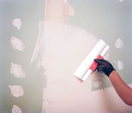 A person is plastering a wall with a spatula