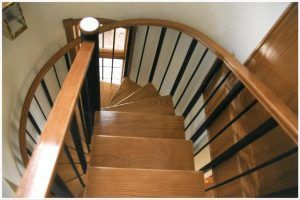 A wooden spiral staircase with a black railing