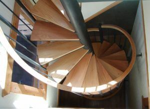 A spiral staircase made of wood and metal with a black railing