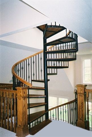 A spiral staircase with wooden steps and a black railing