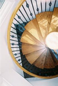 A spiral staircase with wooden steps and a black railing
