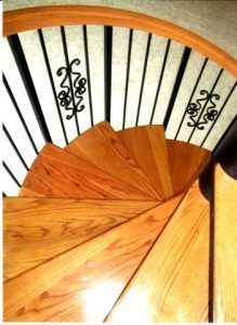 A wooden spiral staircase with a wrought iron railing