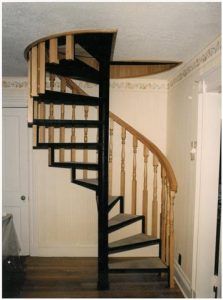 A spiral staircase with a wooden railing in a hallway