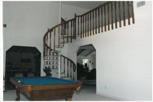 A pool table with a spiral staircase in the background