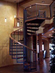 A spiral staircase in a house with a christmas tree in the background