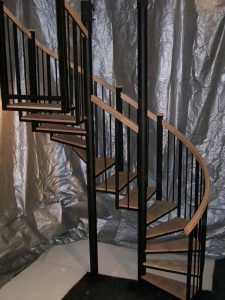 A spiral staircase with wooden steps and a metal railing in a room.