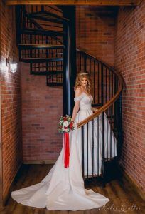 A woman in a wedding dress is standing on a spiral staircase.
