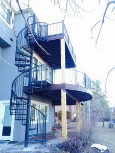 A house with a spiral staircase leading up to a deck.