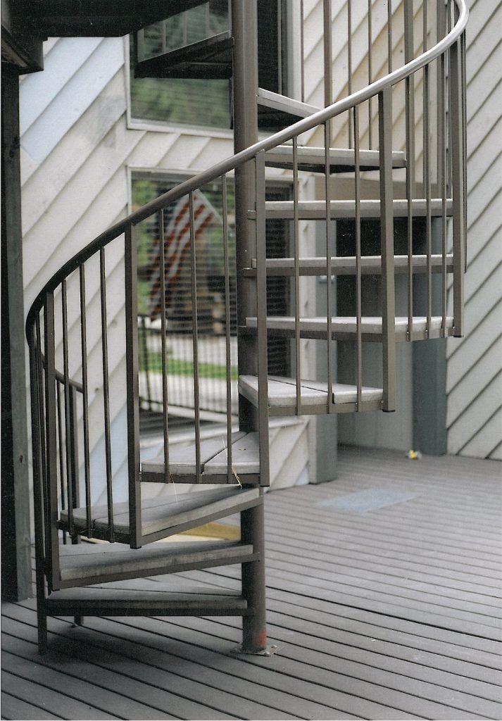 A spiral staircase on a deck outside of a building