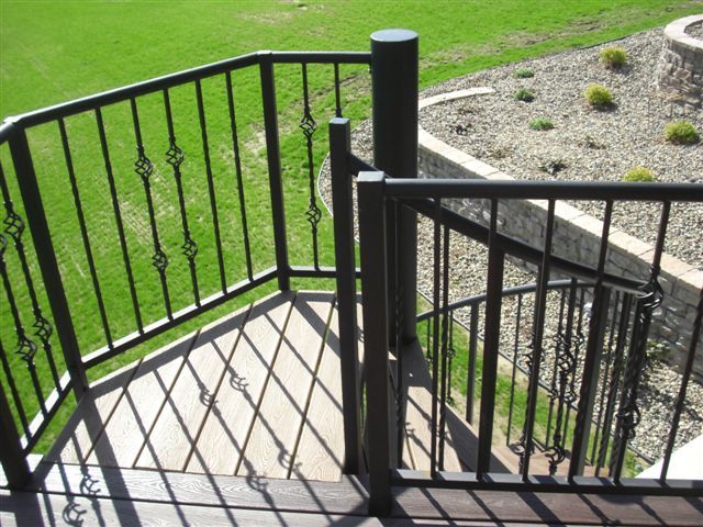 A staircase with a wrought iron railing leading up to a grassy area