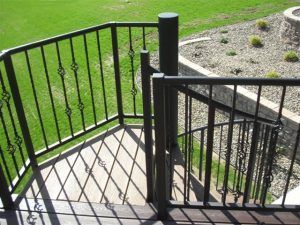 A staircase with a wrought iron railing leading up to a lush green field.