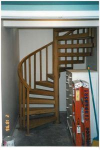 A wooden spiral staircase is in a room with a ladder.