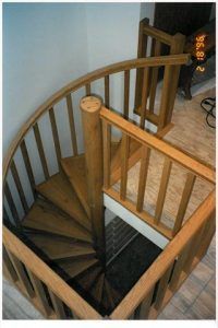 A spiral staircase with a wooden railing is shown from above