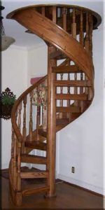 A wooden spiral staircase is in a living room.