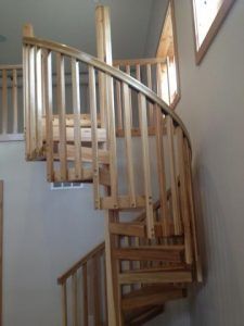 A wooden spiral staircase with a railing in a house.