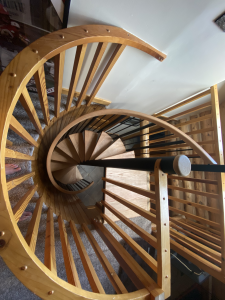 A wooden spiral staircase with a black railing