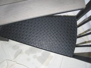 A close up of a black spiral staircase with a diamond pattern on the steps.