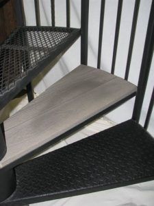 A close up of a spiral staircase with a metal railing and wooden steps.