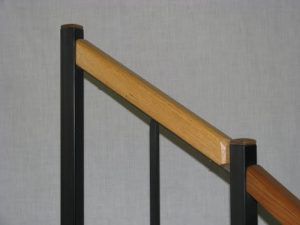 A close up of a stair railing with a wooden handrail