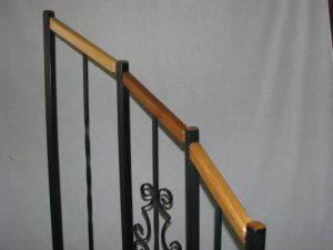 A close up of a stair railing with a wooden handrail