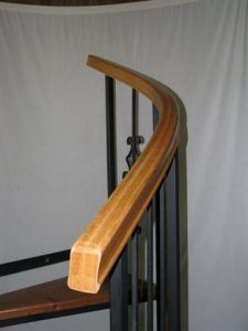 A close up of a wooden railing on a spiral staircase.
