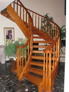 A wooden spiral staircase with a picture of a man on the wall behind it