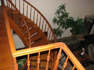A wooden spiral staircase with a wooden railing in a living room