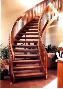 A wooden staircase with a curved railing in a room