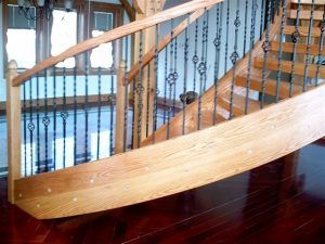 A wooden staircase with a wrought iron railing in a living room.