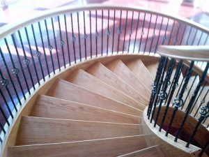 A wooden spiral staircase with a wrought iron railing.
