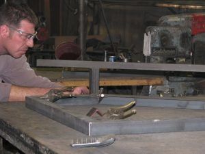 A man is working on a piece of metal on a table.