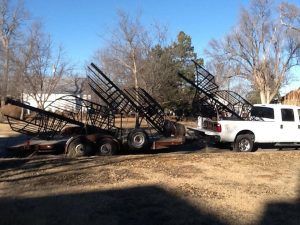 A white truck is parked next to a trailer with stairs on it.