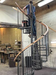 A man is standing on top of a spiral staircase in a workshop.