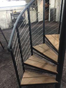 A spiral staircase with wooden steps and a metal railing.