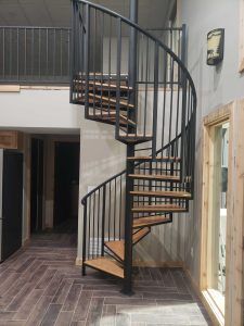 A spiral staircase with wooden steps and a metal railing in a room.