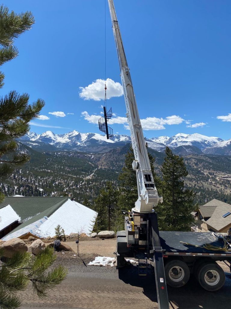 A crane is lifting a telephone pole in the mountains.