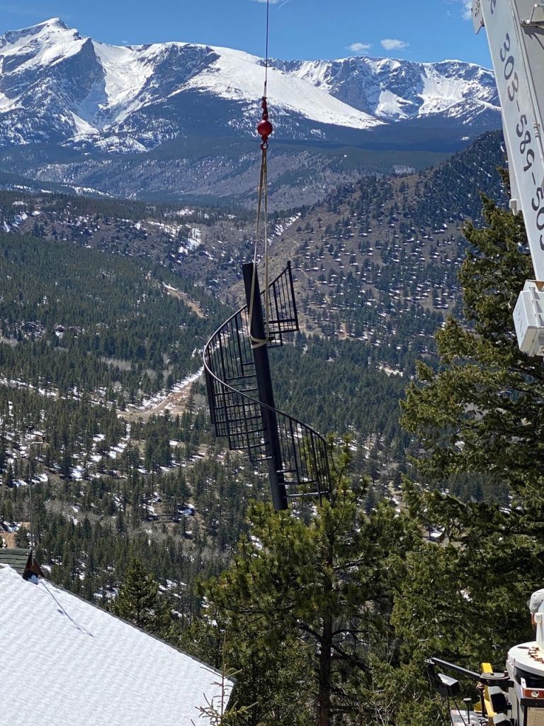 A ski lift is being lifted up to the top of a snow covered mountain.